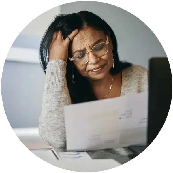 Woman with glasses looking stressed while reviewing financial documents, reflecting the pressures faced by self-employed individuals.